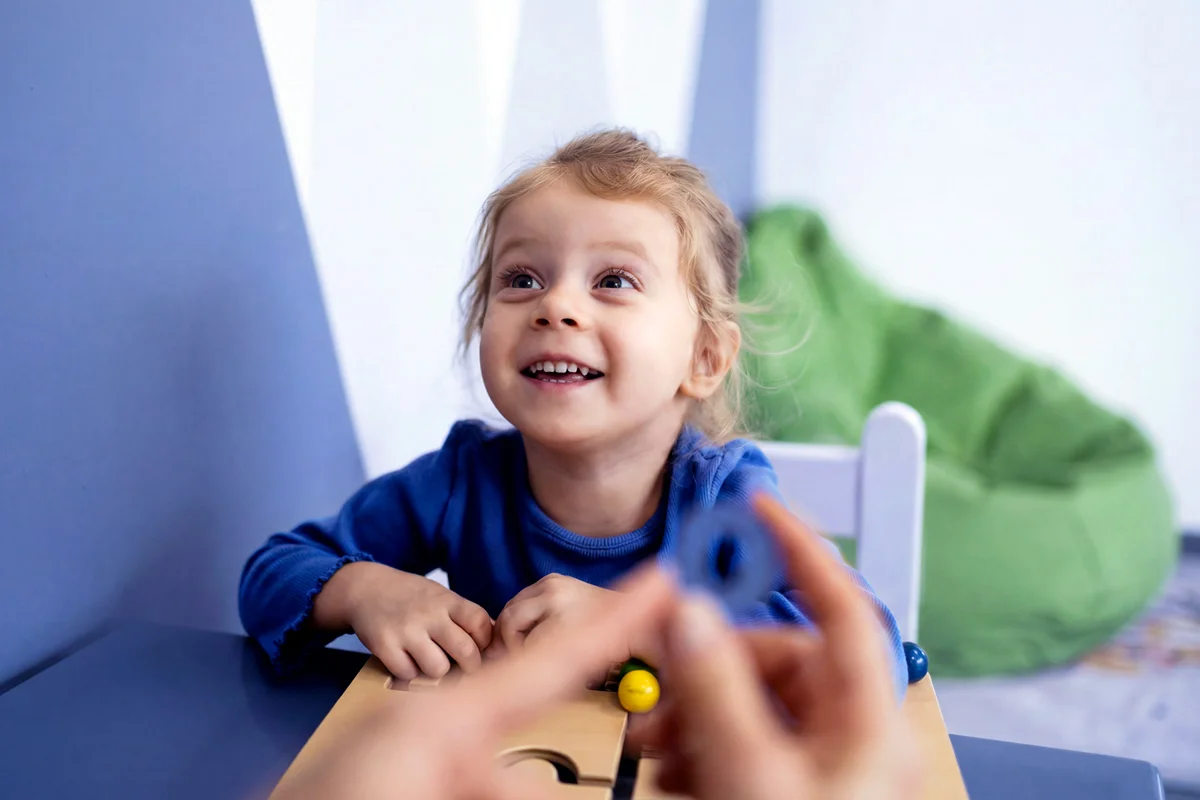 Child smiling with toy at a table