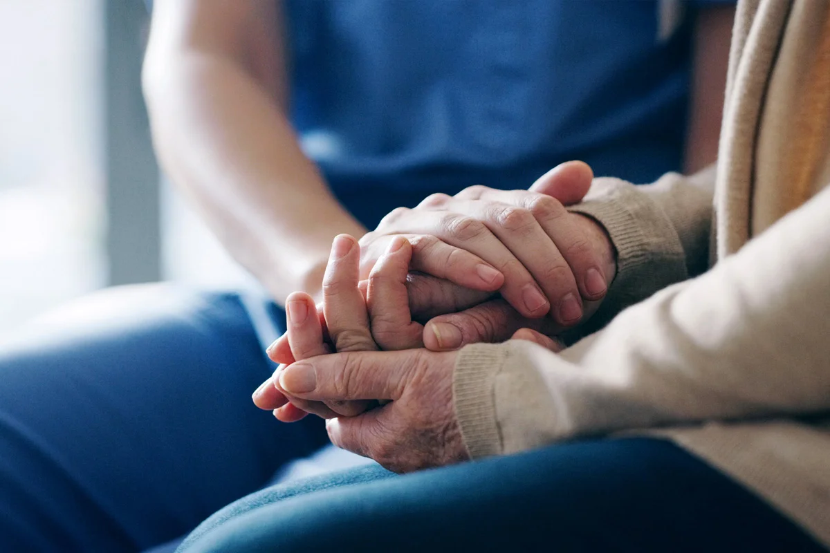Two pairs of hands holding one another
