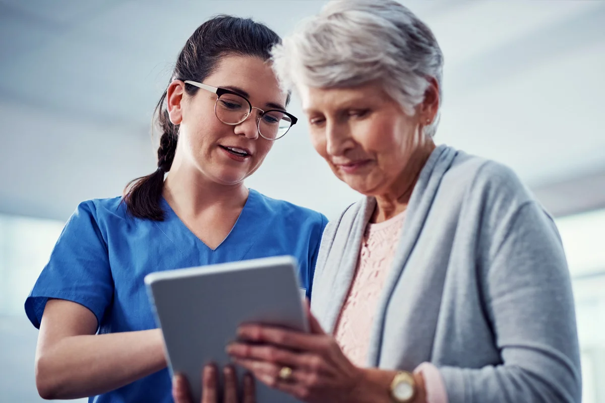 Nurse and old woman looking at a tablet