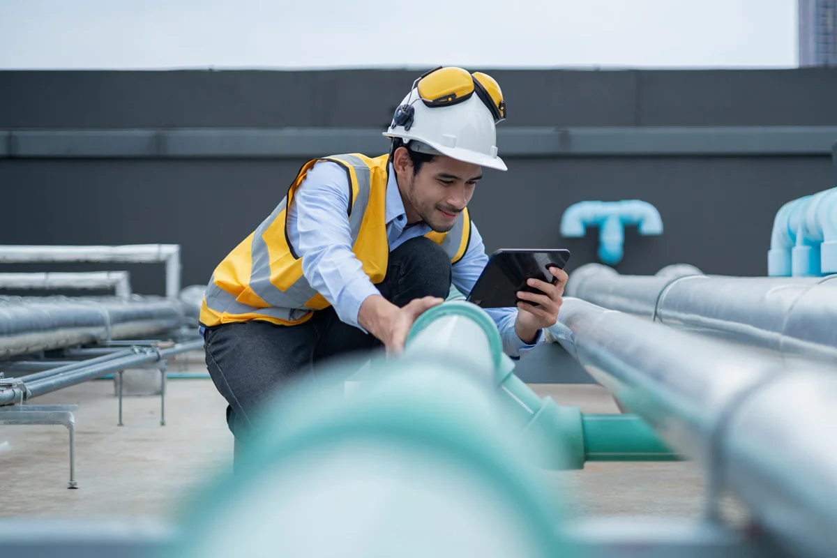 Man in high vis and protective headgear looking at tablet