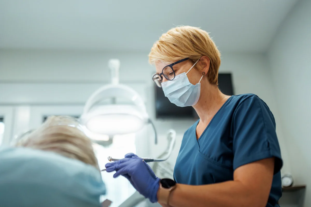 Dentist in glasses using tools on a patient