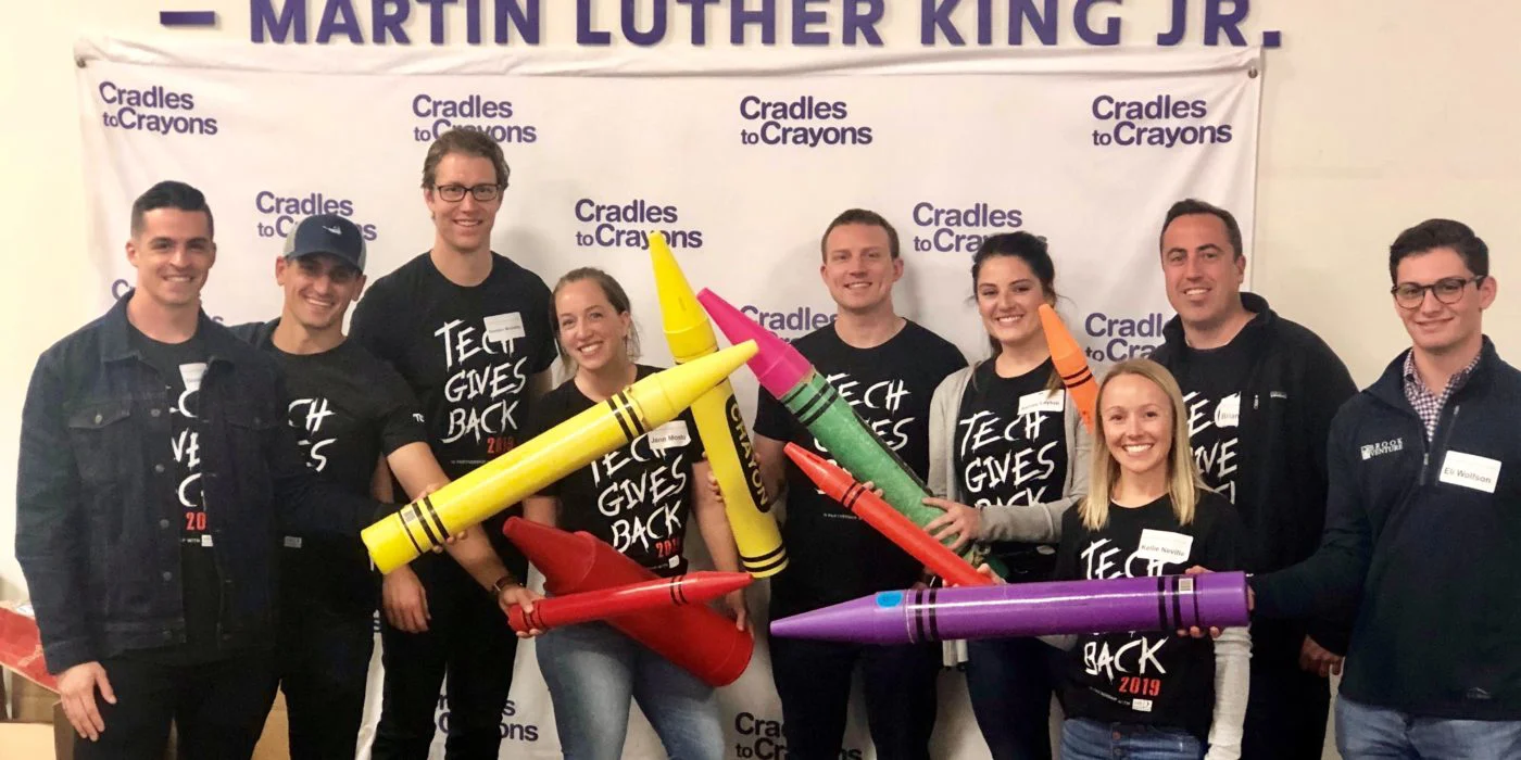 Team posing holding large crayons