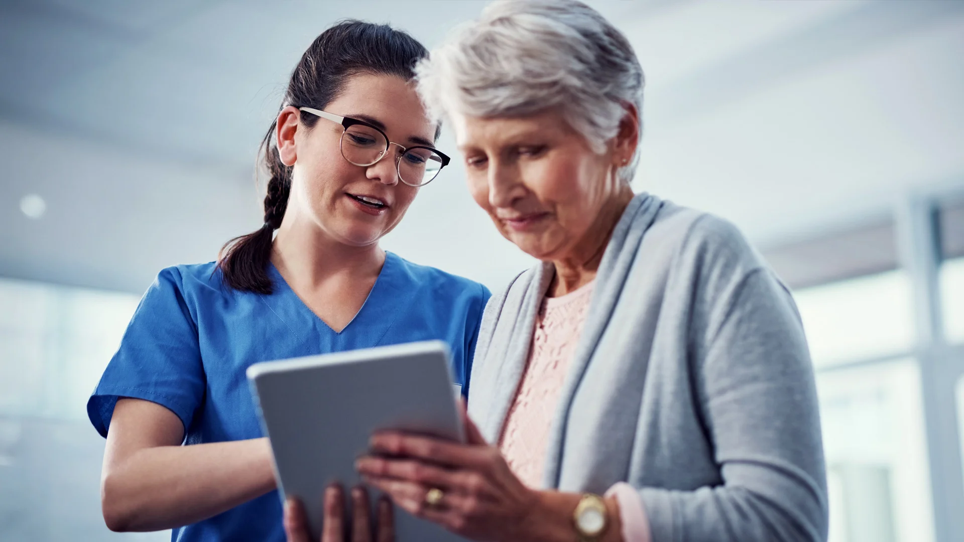 Nurse and old woman looking at a tablet